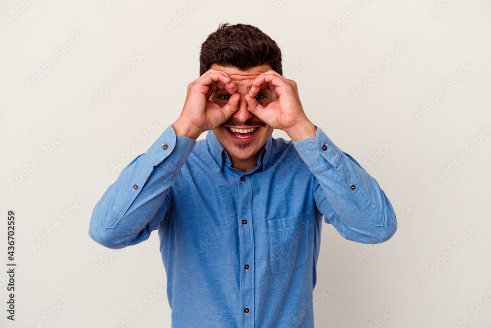 Young caucasian man isolated on white background showing okay sign over eyes Young caucasian man isolated on white background showing okay sign over eyes