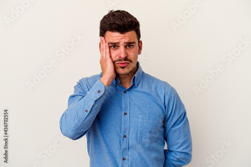 Young caucasian man isolated on white background blows cheeks, has tired expression. Facial expression concept.