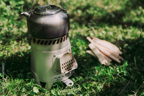 Outdoor cooking concept. Small, portable stove on woods with kettle on