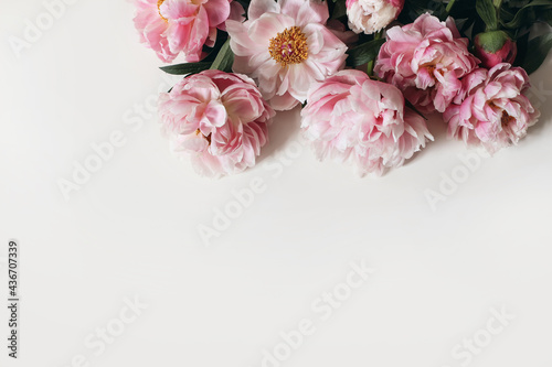 Fototapeta Naklejka Na Ścianę i Meble -  Spring decorative floral corner, banner made of pink peonies flowers isolated on white table background. Empty copy space. Flat lay, top view. Picture for blog. Summer wedding or birthday concept.