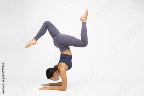 Fototapeta Young Asian woman practicing inversion balancing yoga pose handstand isolated on