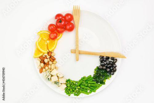 Colorful food and cutlery arranged in the form of a clock on a plate. Intermittent fasting, diet, weight loss, lunch time concept. photo