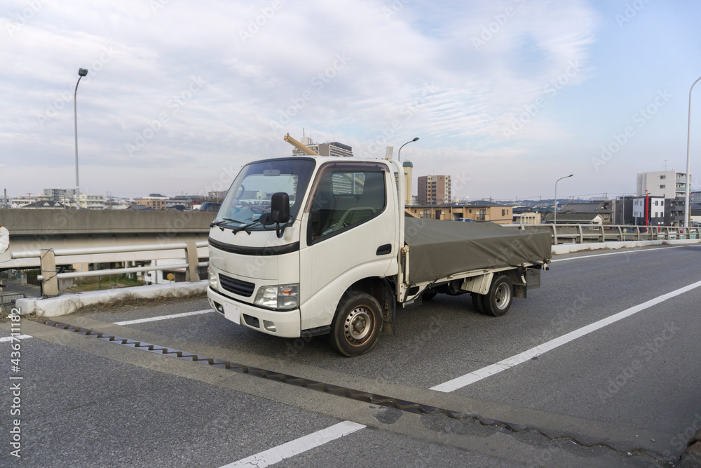 荷台にグリーンシートを覆う平ボディトラック