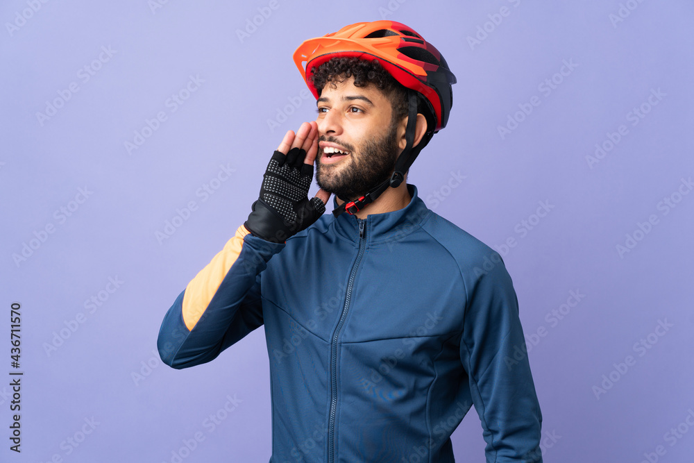 Obraz premium Young Moroccan cyclist man isolated on purple background shouting with mouth wide open to the side