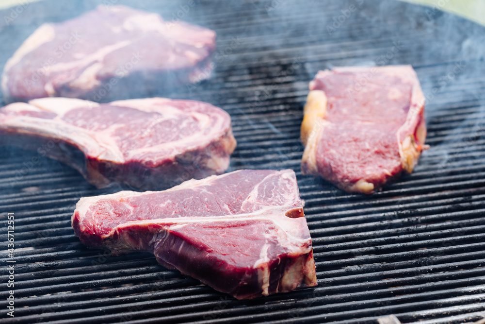 Selection of dry aged steak that includes t bone, rib eye and rump steak on a barbecue Selection of dry aged steak that includes t bone, rib eye and rump steak on a barbecue