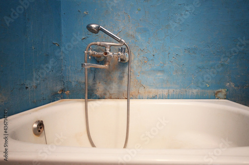 Old vintage dirty water tap in broken bathroom. Trash repairs. Grunge wall background.