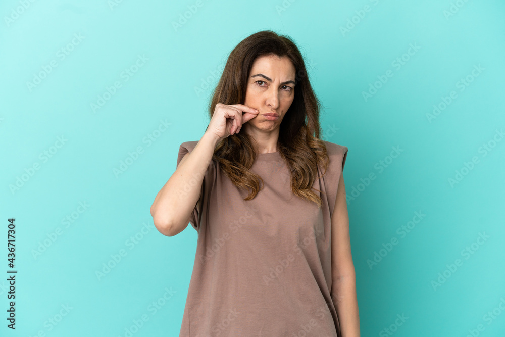 Middle aged caucasian woman isolated on blue background showing a sign of silence gesture Middle aged caucasian woman isolated on blue background showing a sign of silence gesture