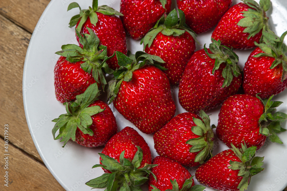 Strawberries in a plate on a wooden table. Ripe fresh strawberries. Healthy diet. Strawberries in a plate on a wooden table. Ripe fresh strawberries. Healthy diet.