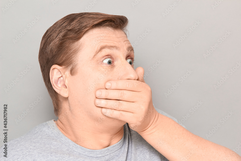 Portrait of shocked frightened man covering mouth with hand Portrait of shocked frightened man covering mouth with hand