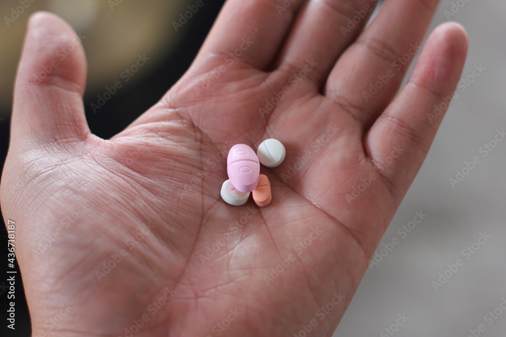 close up of asian man's hand holding some pills close up of asian man's hand holding some pills