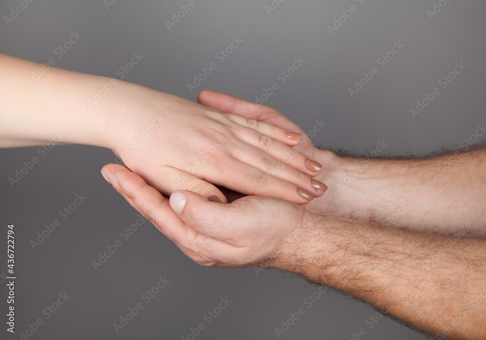 Hands of man and woman holding together, Gray background.