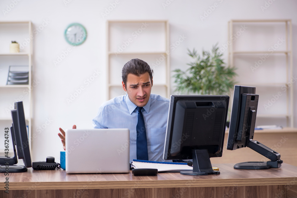 Young male employee unhappy with excessive work Young male employee unhappy with excessive work