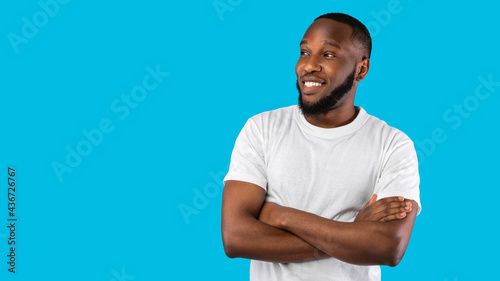 African American Man Posing Crossing Hands Looking Aside, Blue Background