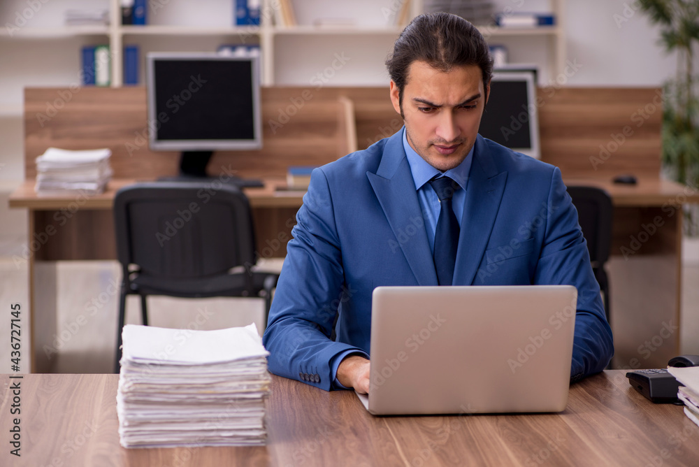 Young male employee and a lot of work in the office Young male employee and a lot of work in the office