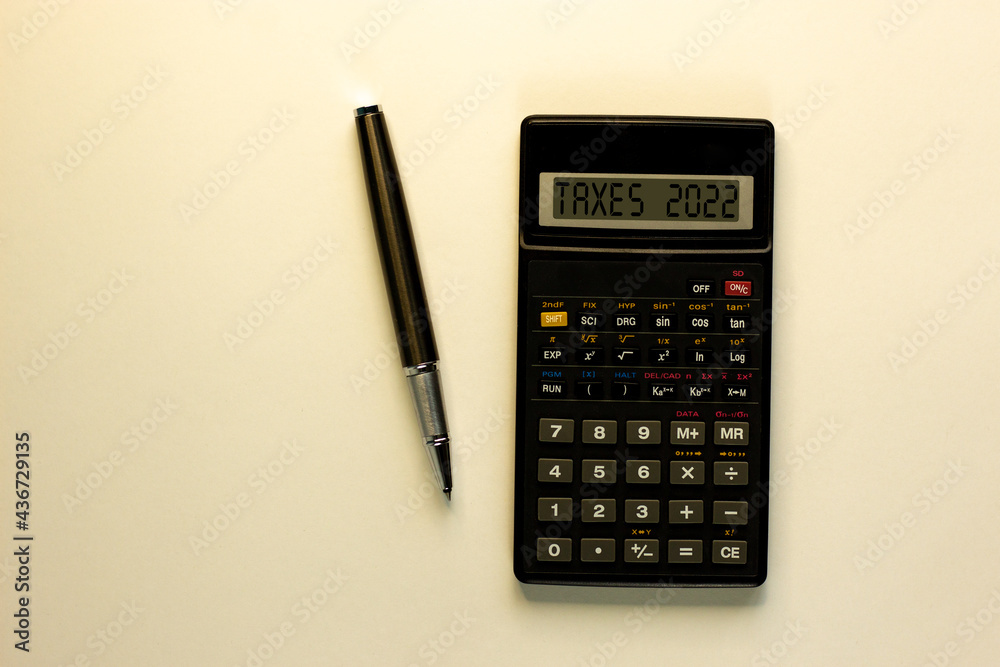 Business concept of taxes planning 2022. Calculator with words 'taxes 2022', metalic pen. Business, taxes 2022 concept. Beautiful white background, copy space. Business concept of taxes planning 2022. Calculator with words 'taxes 2022', metalic pen. Business, taxes 2022 concept. Beautiful white background, copy space.