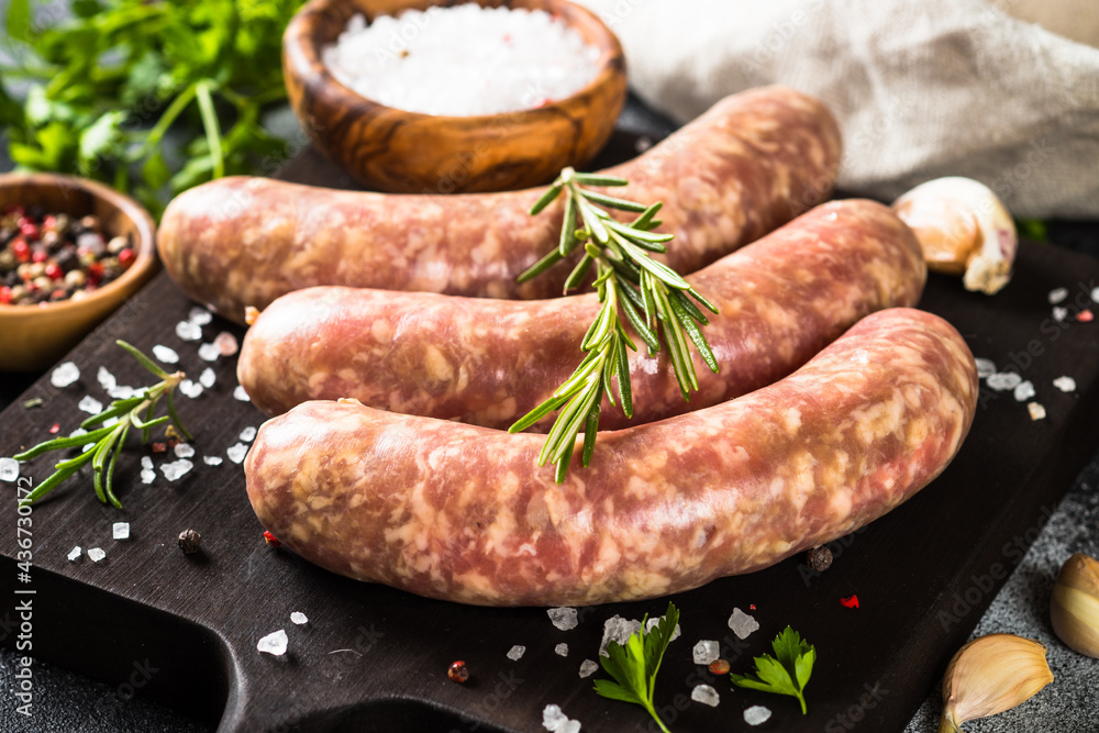 Bratwurst or sausages on cutting board with spices and herbs. Bratwurst or sausages on cutting board with spices and herbs.