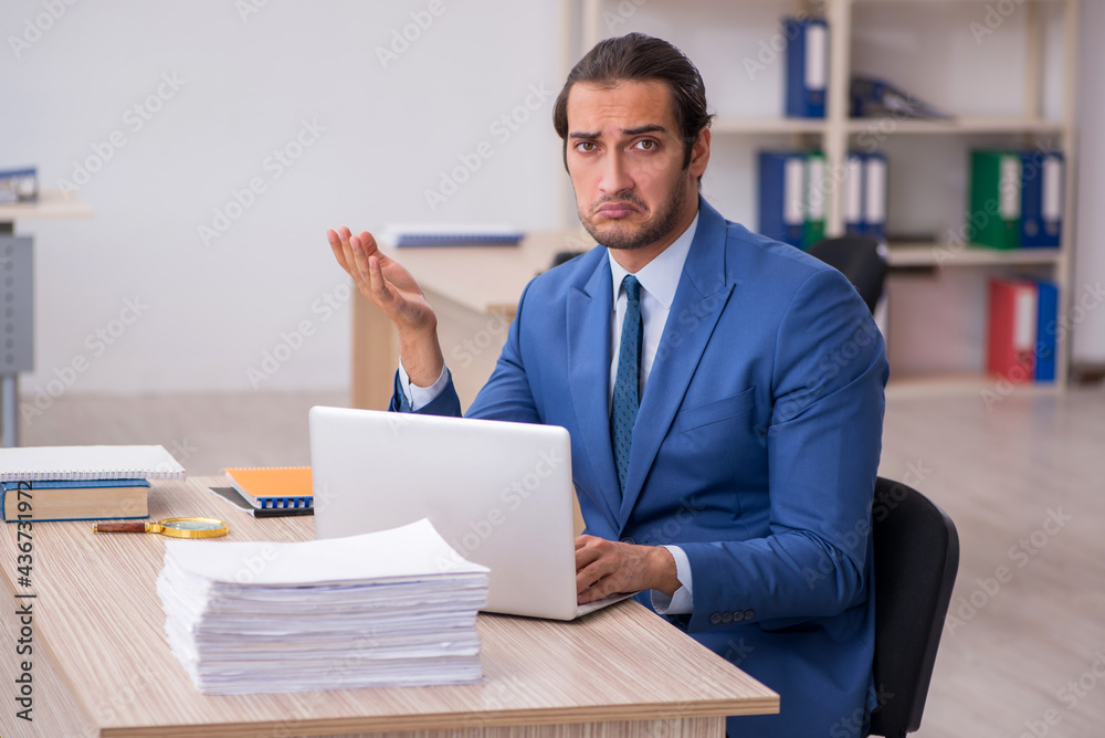 Young male employee and too much work in the office Young male employee and too much work in the office