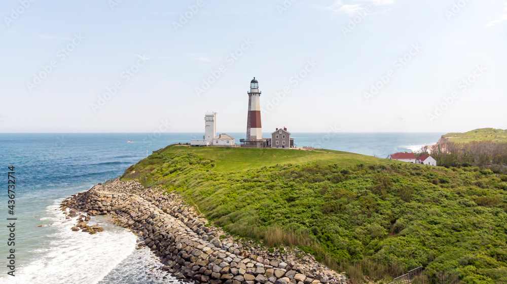 White lighthouse with brick on the ocean with a green lawn