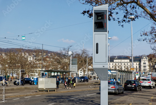 stationary radar speed camera camera in big city with cars and people in blurred background, speed controls are important to ensure traffic safety, daytime, sunset
