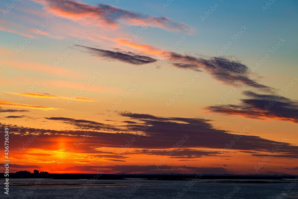 Sunset on the river. Colorful landscape with river and blue sky with multicolored clouds. River sunset panorama