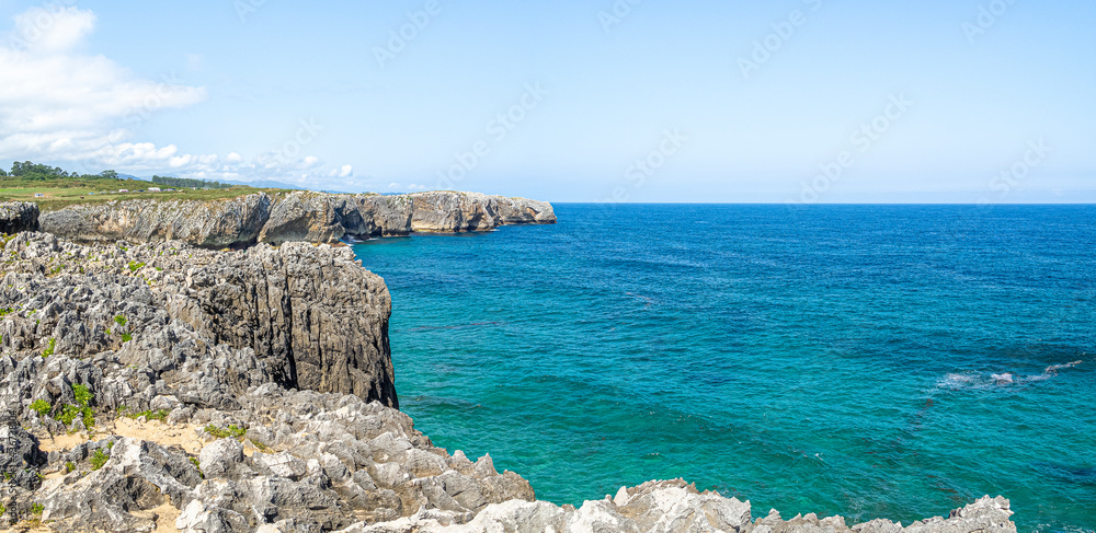 Paisaje panorámico de los Bufones de Pría en Asturias, España, verano de 2020. Con las vistas de los acantilados pedregosos y el mar con aguas azules y aguamarina.