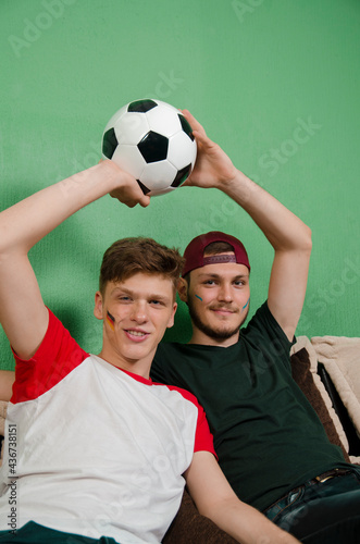 Portrait , handsome teenage brothers sitting on couch with soccer ball 