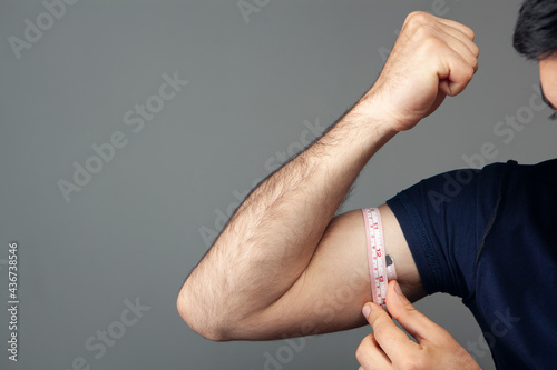 a man measures the girth of his arm with a meter