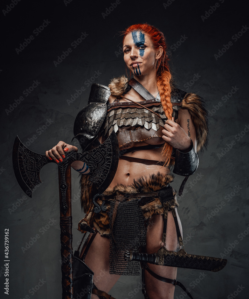 Serious nordic female warrior with axe and armour in dark background Serious nordic female warrior with axe and armour in dark background