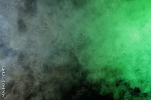 Artificial smoke in grey-green light on black background