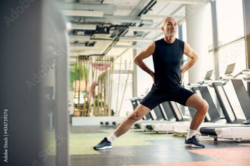 Mature athletic man warming up for sports training while exercising in a gym.