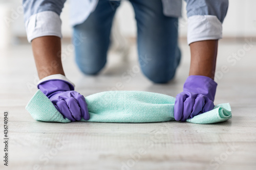Unrecognizable black guy cleaning floor, wearing rubber gloves