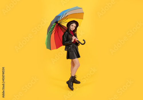 kid in hat with rainbow umbrella. autumn season. rainy weather forecast. © Olena