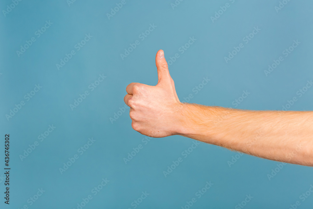 Close-up photo of man showing thumbs up. Isolated over blue background.