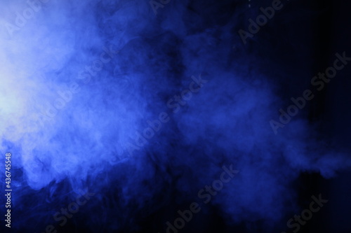 Artificial smoke in blue light on black background
