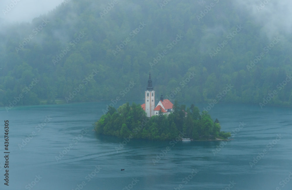 Island with church on Lake Bled on a foggy day from bird's eye perspective