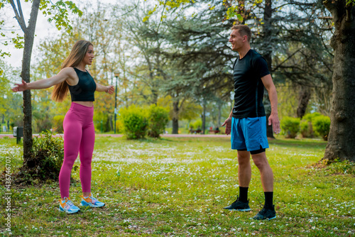 Fototapeta Naklejka Na Ścianę i Meble -  Couple in sportswear exercise and stretch muscles in a park