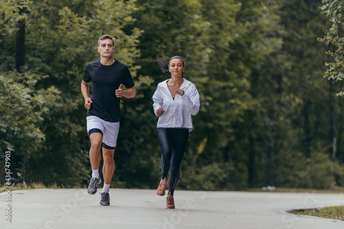 Athletic couple running on a street next to each other. Nature,fit and healthy concept.