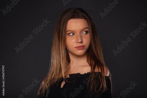 Close up portrait of a sexy female model looking serious while posing in black clothes inside a studio