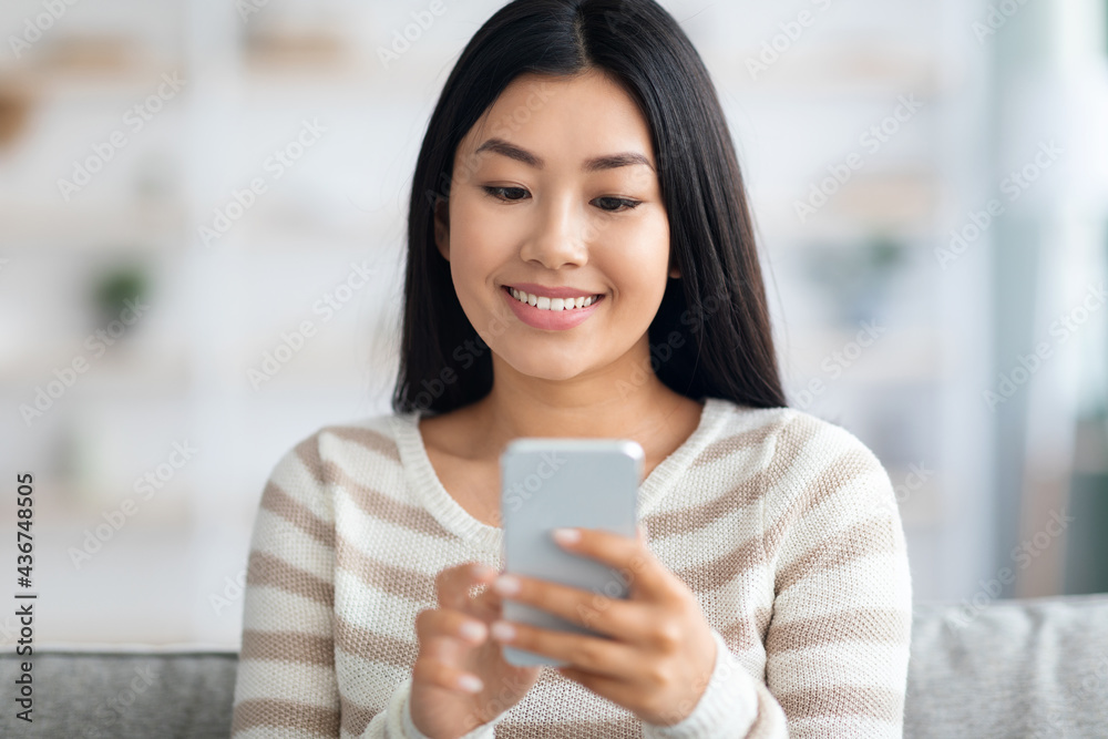 Beautiful Smiling Young Korean Woman Using Smartphone While Relaxing At Home Beautiful Smiling Young Korean Woman Using Smartphone While Relaxing At Home