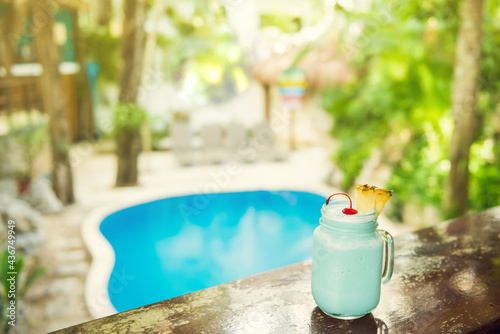 Colorful tropical cocktails on wooden bar. Mixology in pool holiday setting. Caribbean cocktails. Colorful cocktails in caribbean bar hotel.