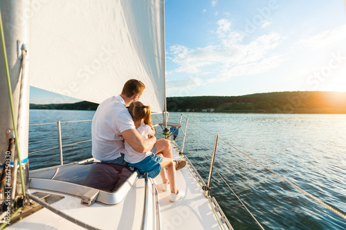 Father And Daughter Sailing On Yacht Sitting On Deck, Back-View © Prostock-studio