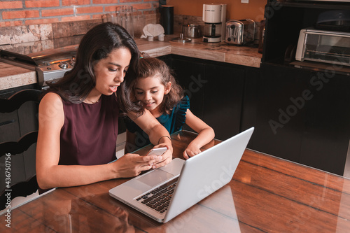 Young mother working at home and helping daughter