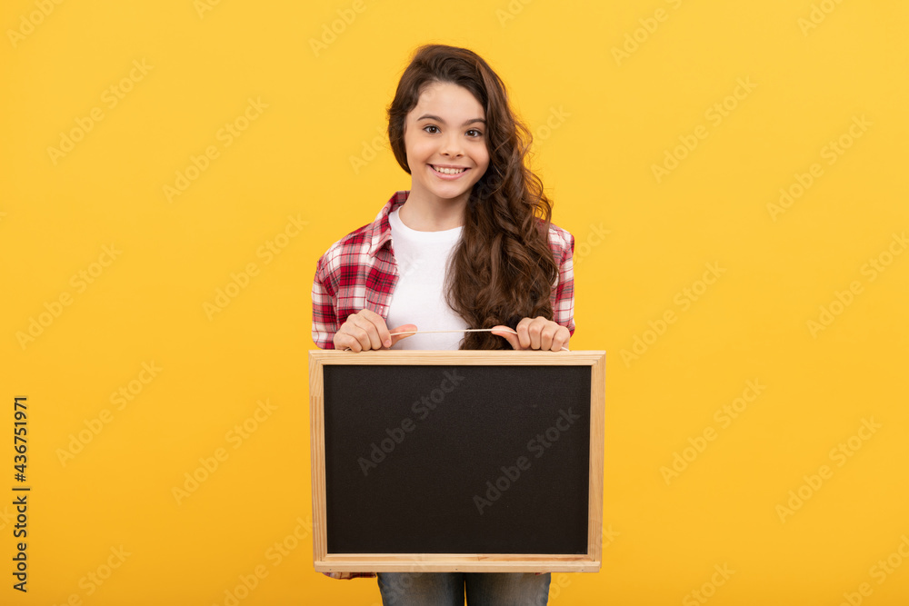 Naklejka premium happy teen girl hold blackboard. child advertising. back to school. presenting novelty information.