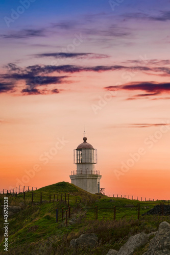 Landscape with an old lighthouse on the background of the sunset.