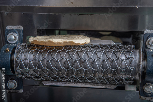 machine to make tortillas Mexican tortilleria with metal band and a kilo of tortillas wrapped in white paper photo