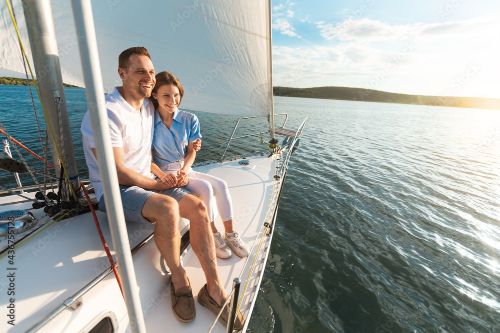 Smiling Couple Embracing Sitting On Yacht Deck Looking At Seascapes
