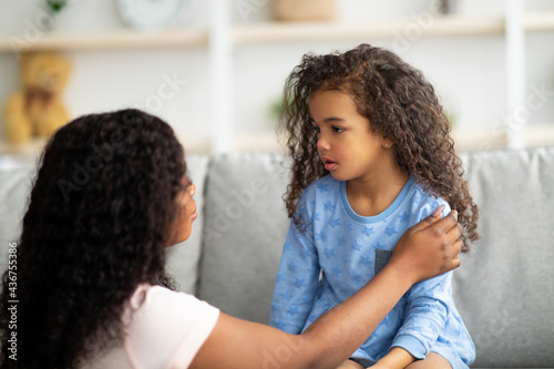 Millennial black mom supporting angry and upset little daughter, consoling her at home. Family conflicts