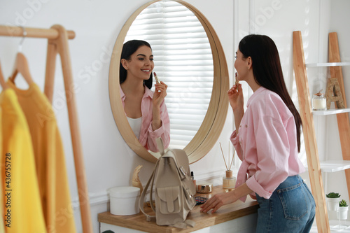 Young woman doing makeup near mirror at home. Morning routine photo