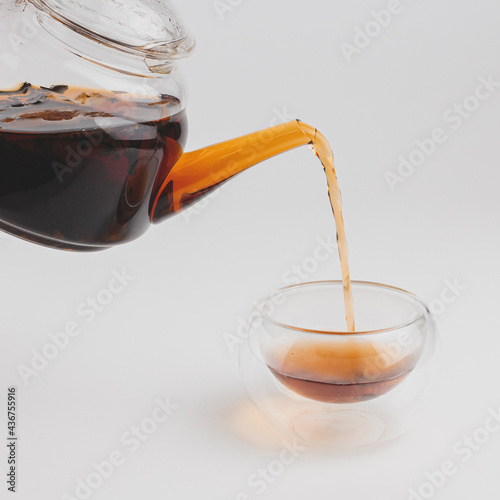 the moment of pouring pu-erh from the teapot into the cup glass
