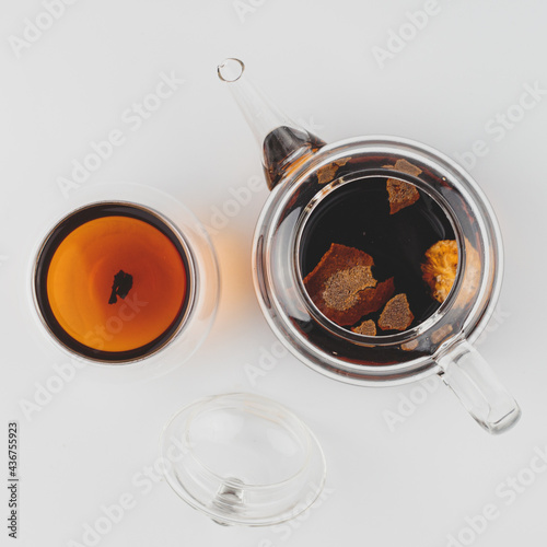 brewed pu-erh in tangerine in a teapot, next to a cup of tea flatlay